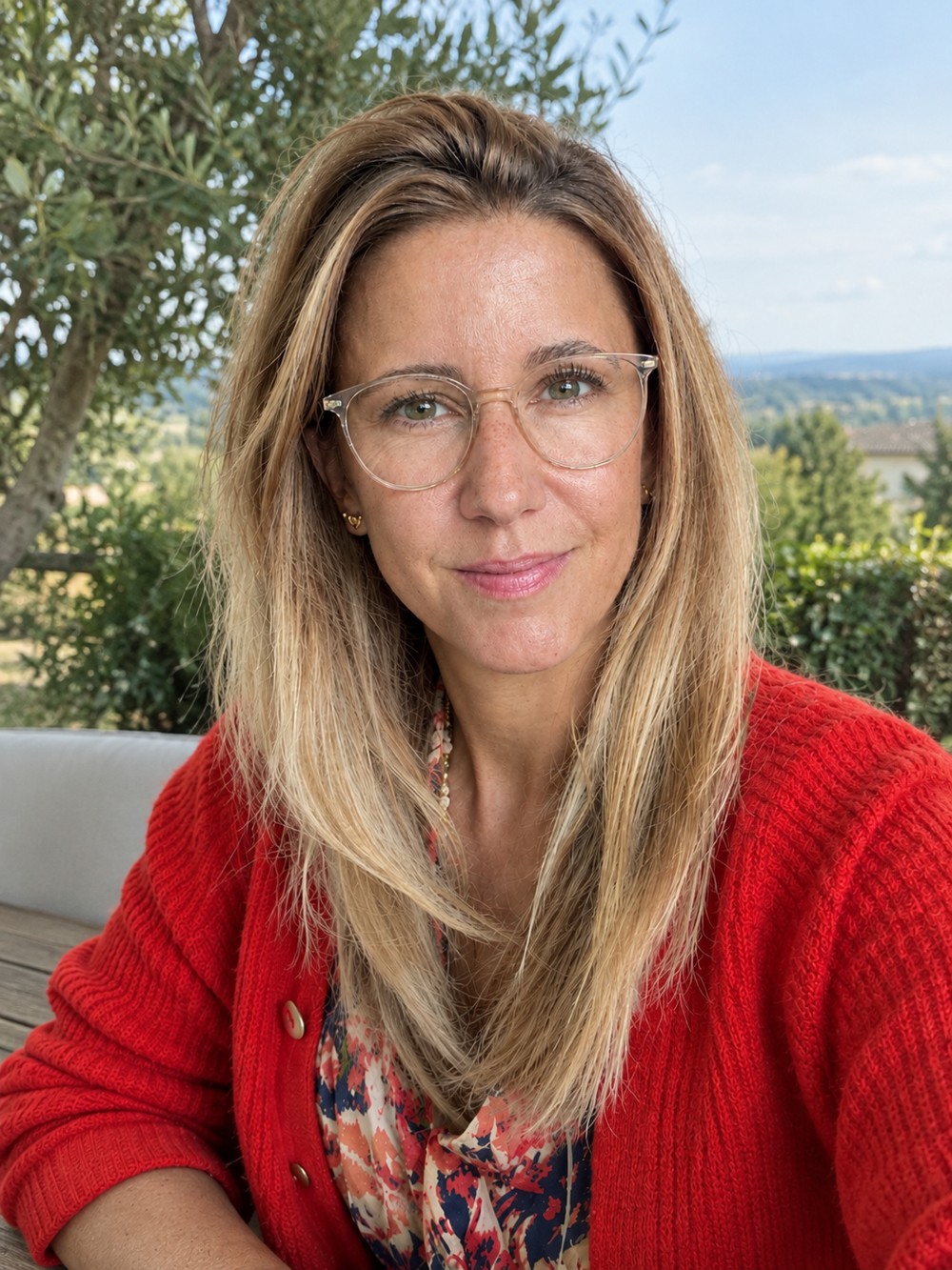 Nora Mayer dans le jardin, vêtue d’un pull rouge